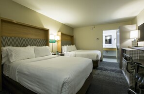 A hotel room with two beds, a desk, a chair, a mirror, and a bathroom visible through an open door. - Holiday Inn & Suites Chicago North Shore (Skokie) by IHG (Skokie)