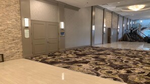 A hotel lobby with a patterned carpet, a stone wall, and a staircase in the background. - Holiday Inn & Suites Chicago North Shore (Skokie) by IHG (Skokie)