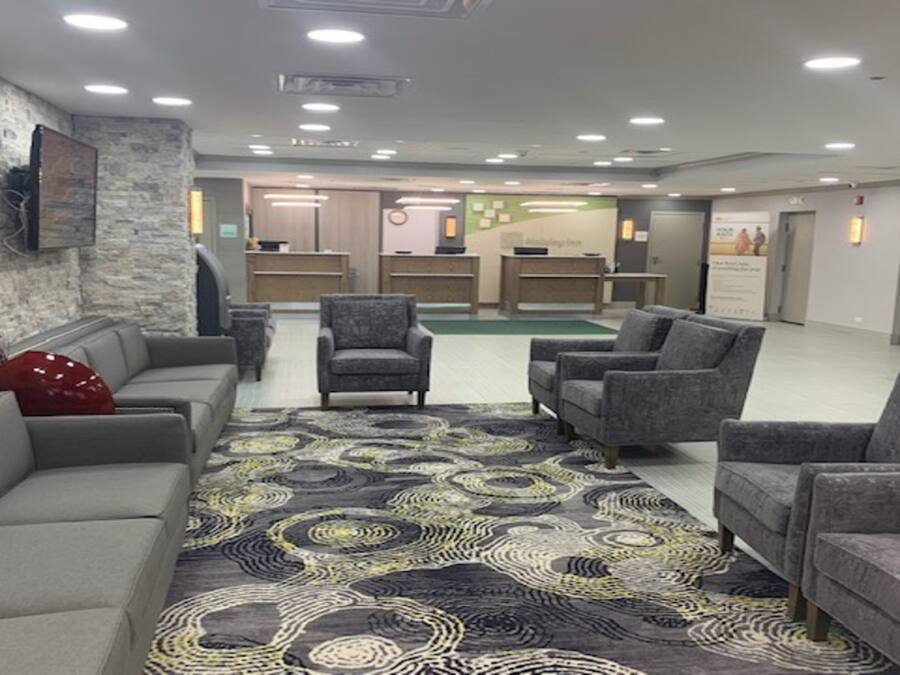 A lobby with a grey sofa, armchairs, a patterned rug, and a reception desk.