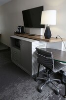 Una habitación de hotel con un escritorio, una silla, un televisor y una lámpara.