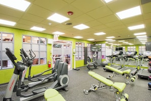 Un gimnasio con diverso equipo de ejercicio, incluyendo cintas de correr y máquinas de pesas.