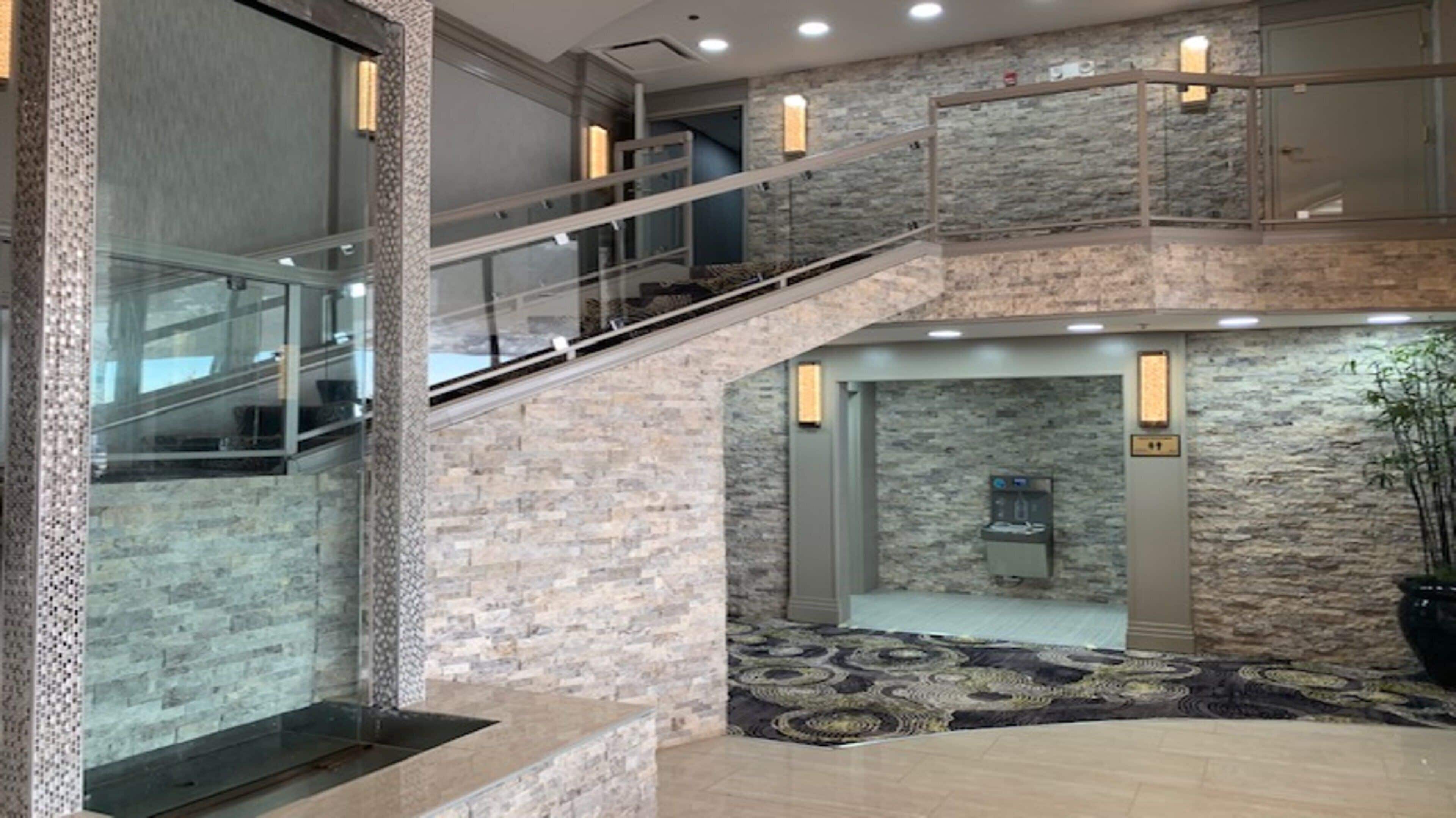 A multi-level interior with a staircase, stone walls, and a water dispenser.