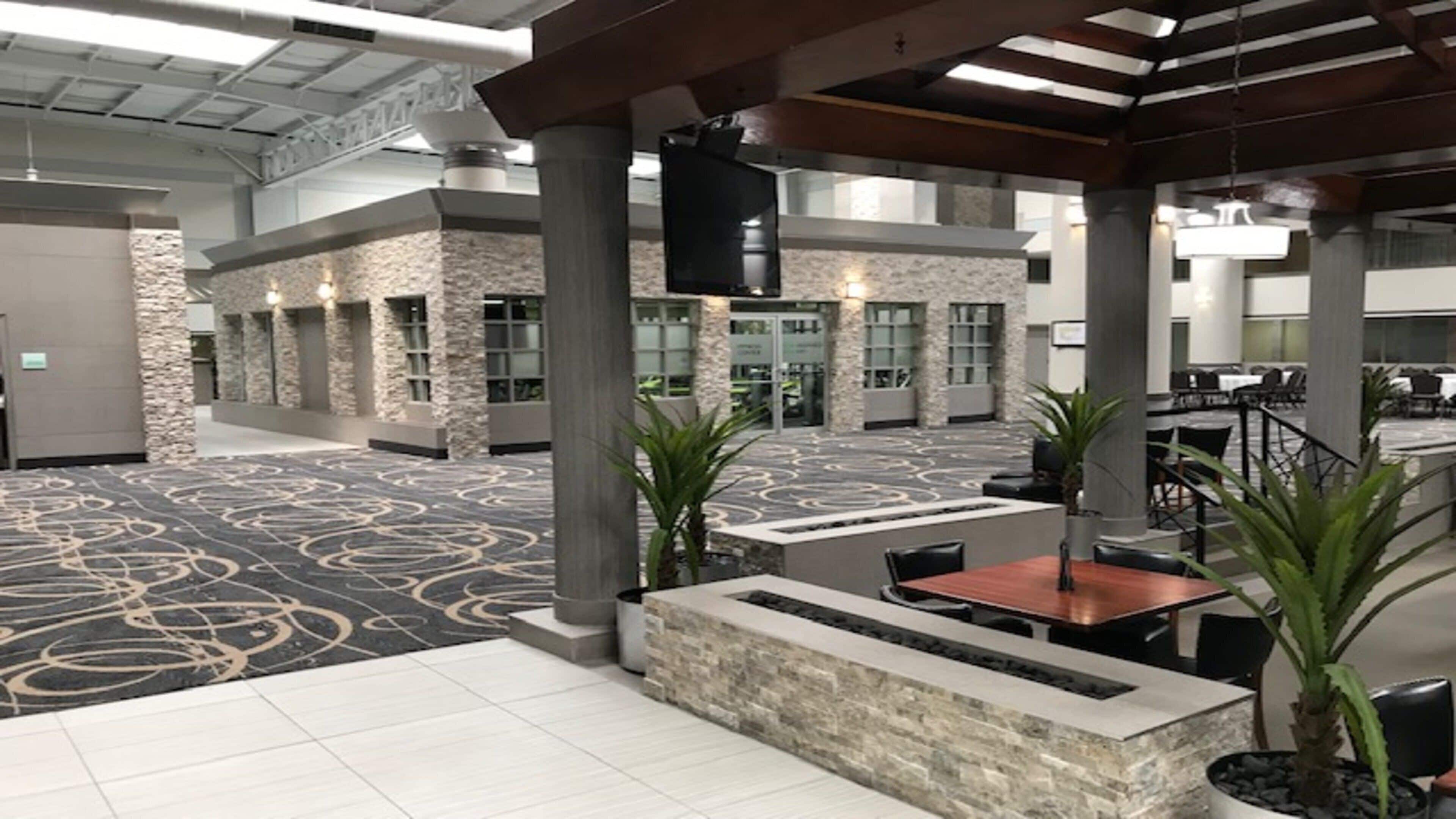 Un vaste espace intérieur doté d’un tapis à motifs, de piliers en pierre et d’un coin salon avec des tables et des chaises.