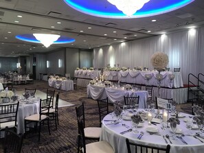 A banquet hall with round tables set for a formal event, featuring white tablecloths, floral centerpieces, and candle lighting. - Holiday Inn & Suites Chicago North Shore (Skokie) by IHG (Skokie)