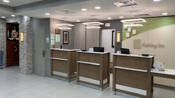 A reception area with three wooden reception desks, a stone pillar, and a Holiday Inn sign.