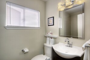 A bathroom with a toilet, sink, and window with blinds.