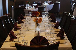 A formal dining table set for a meal with multiple chairs, a vase of flowers, and a variety of tableware.