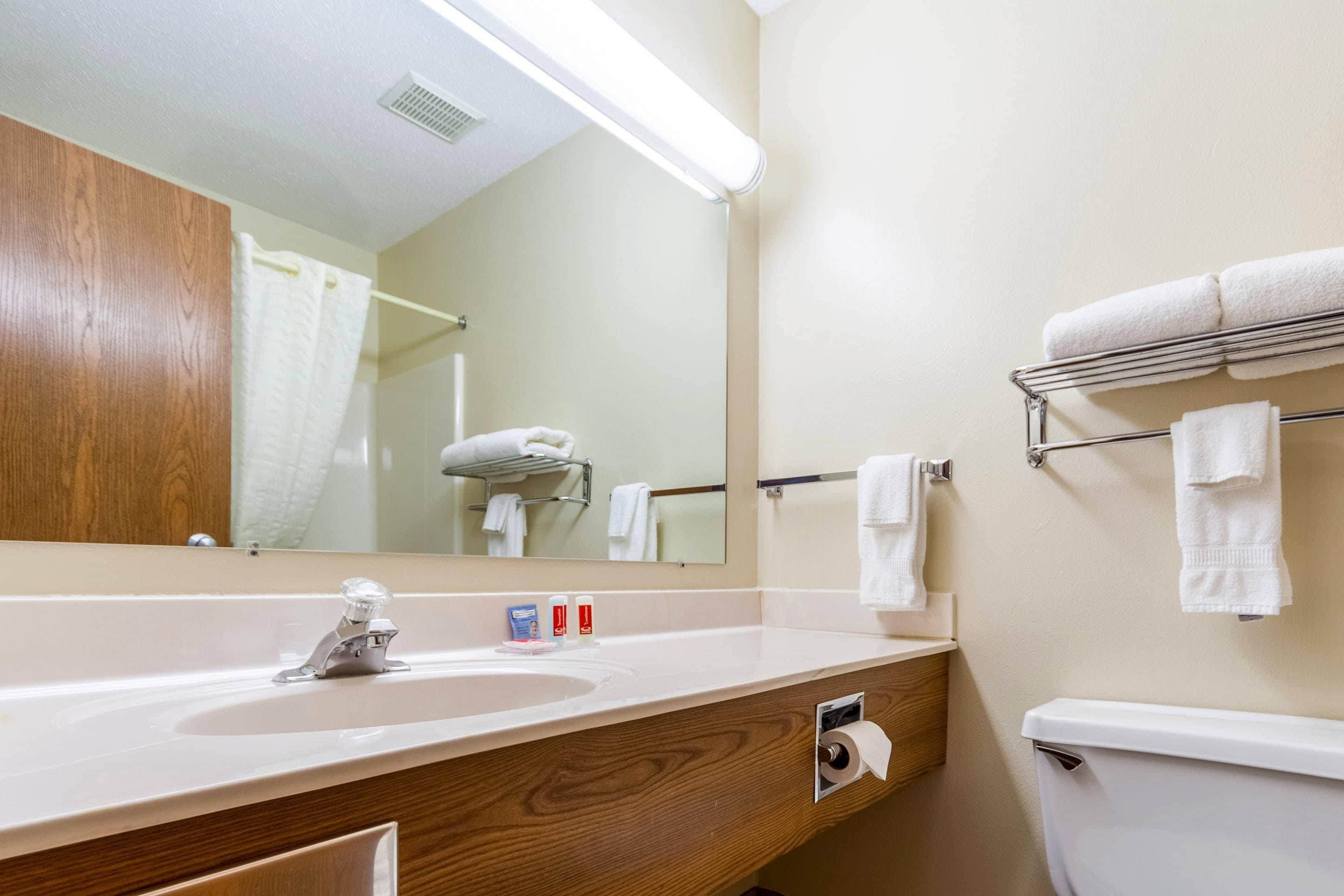 A bathroom with a sink, mirror, towel rack, and toilet.