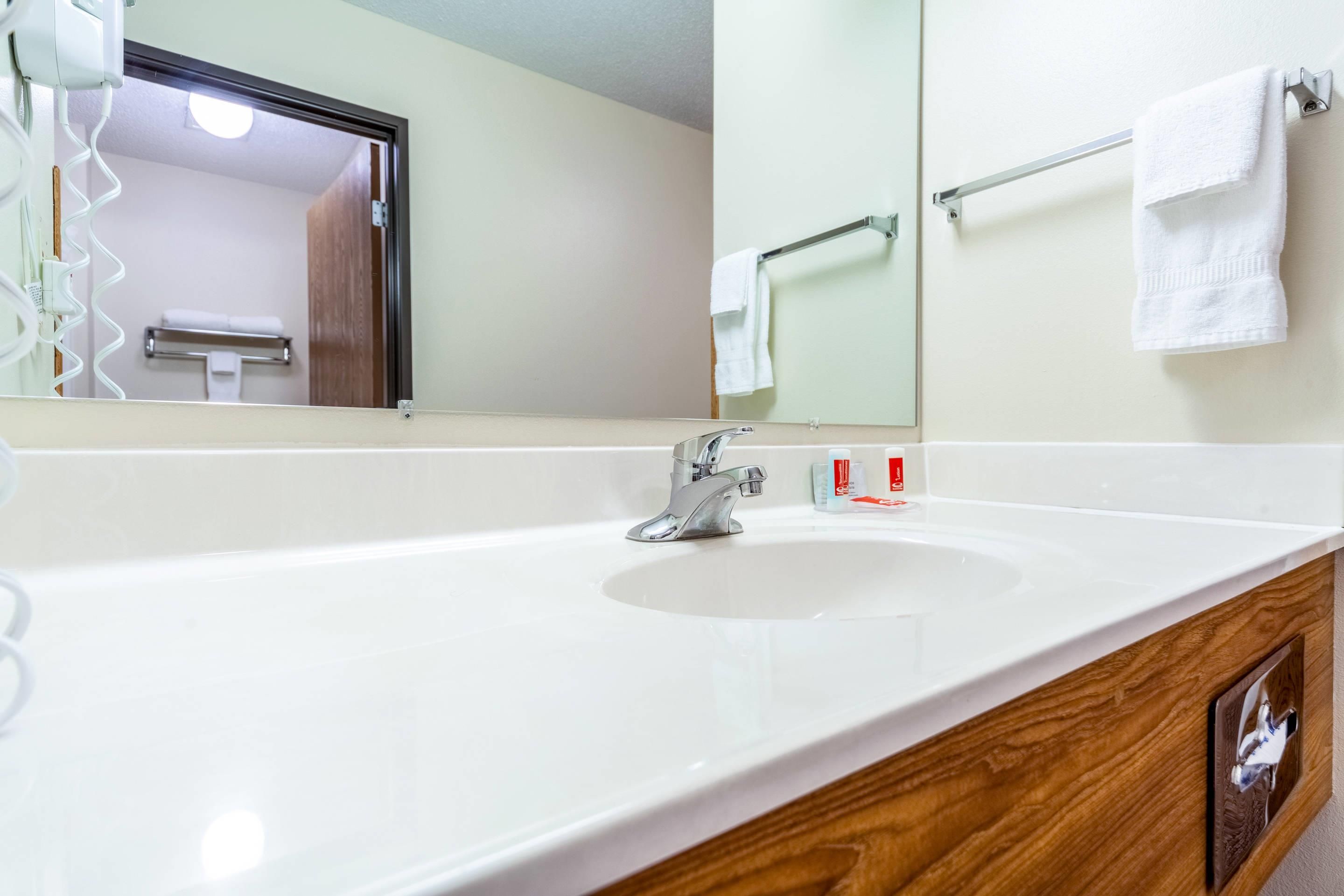 Un baño de hotel con un lavabo blanco, un espejo y un perchero para toallas.