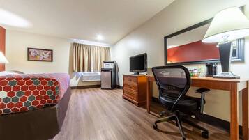 A hotel room with a bed, desk, chair, television, and a mirror.