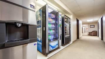 A hotel corridor with vending machines, a water dispenser, and a carpeted floor.