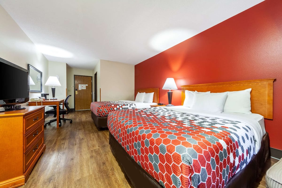 A hotel room with two beds, a desk with a computer, a chair, and a dresser.