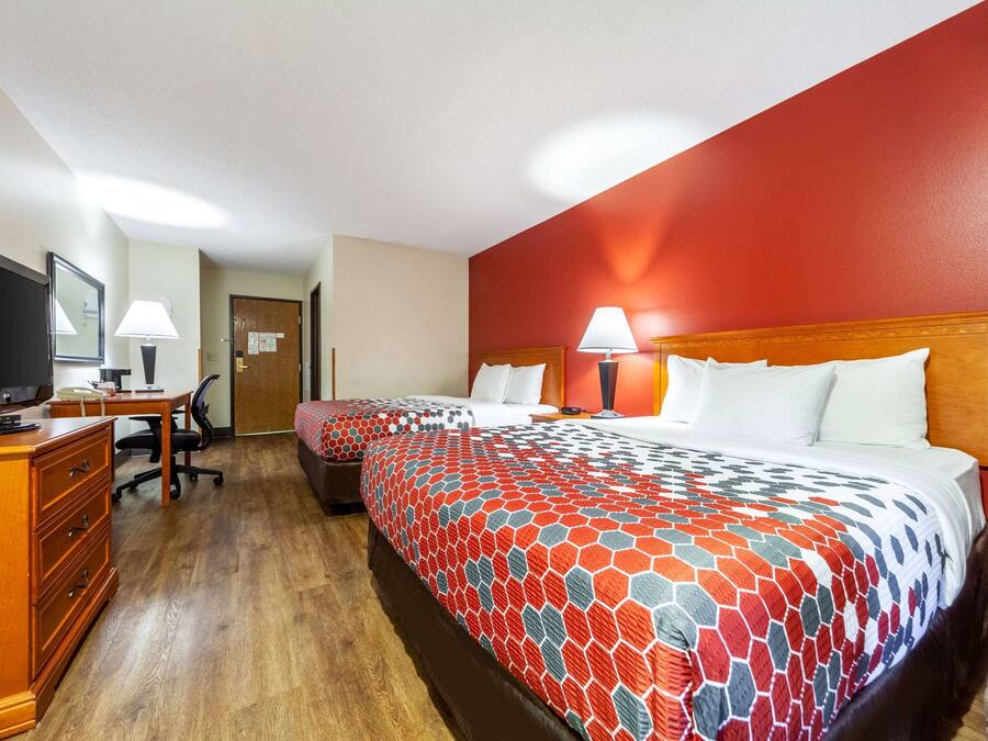 A hotel room with two beds, a desk with a computer, a chair, and a dresser.