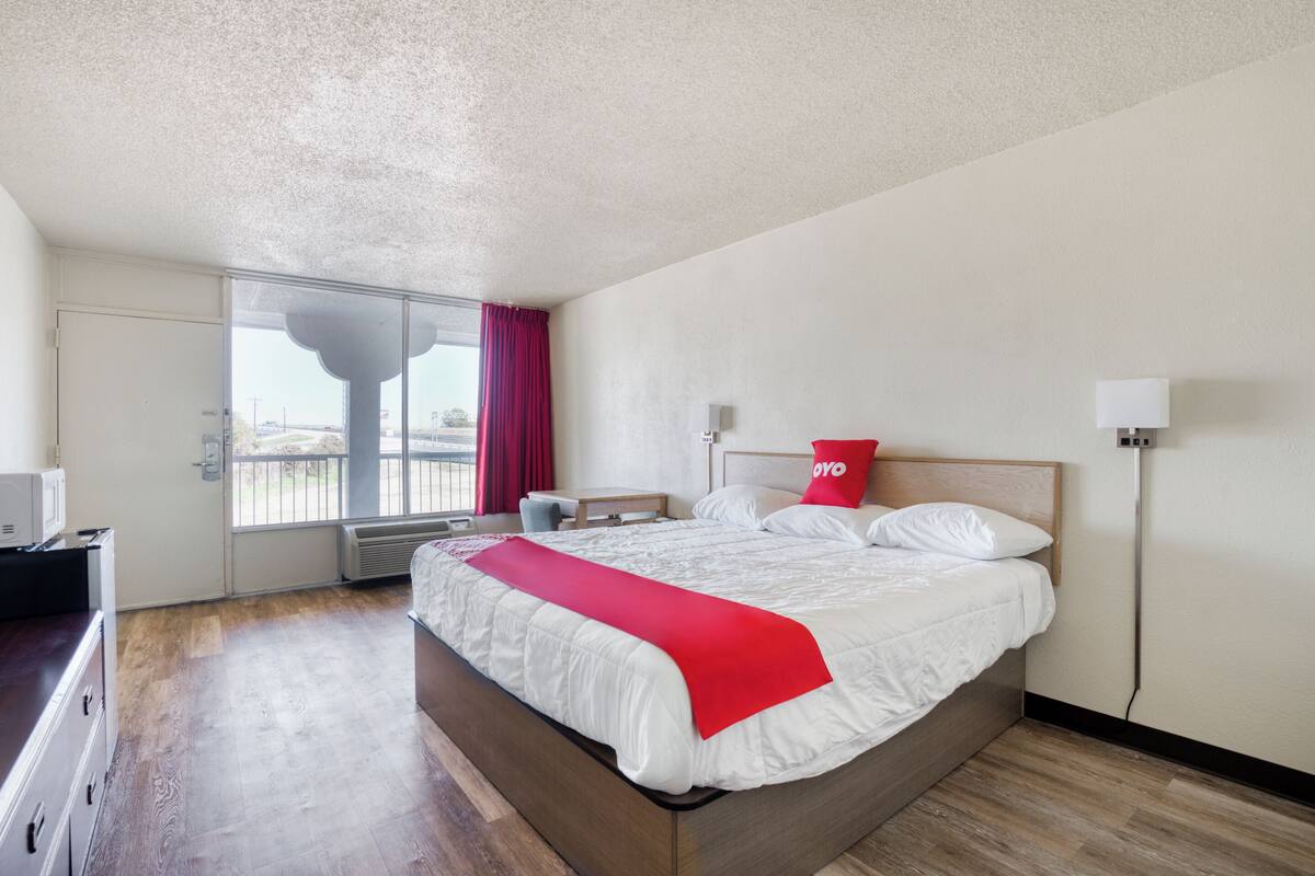 Ein Hotelzimmer mit einem Bett, einem Schreibtisch, einem Stuhl, einem Fenster mit Blick und einer Tür.