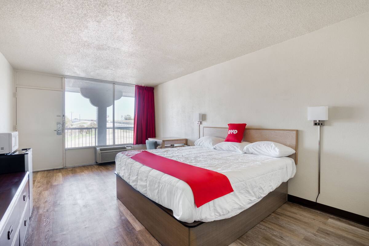 Ein Hotelzimmer mit einem Bett, einem Schreibtisch, einem Stuhl, einem Fenster mit Blick und einer Tür.