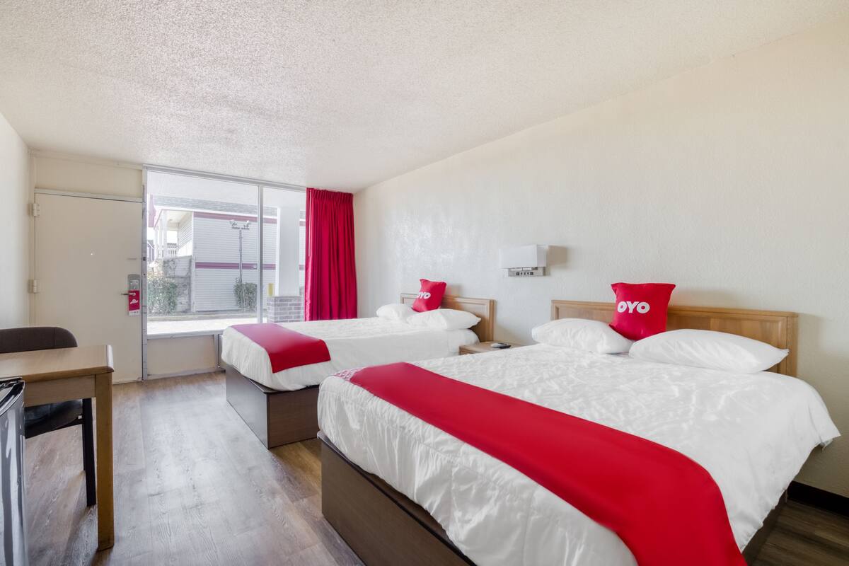 Ein Hotelzimmer mit zwei Betten, einem Schreibtisch und Blick nach außen.