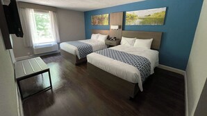 A hotel room with two beds, a small table, and a window with curtains. - Wingate by Wyndham Columbia/Fort Jackson (Columbia)