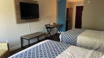 Ein Hotelzimmer mit zwei Betten, einem Schreibtisch, einem Fernseher und einem Bücherregal.