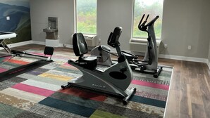 A gym with cardio machines, a wall-mounted air conditioning unit, and a colorful rug. - Wingate by Wyndham Columbia/Fort Jackson (Columbia)