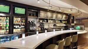 Eine moderne Bar mit einer gebogenen Theke, verschiedenen Sitzgelegenheiten und einer Auswahl an Getränken und Gläsern, die in Regalen präsentiert werden.