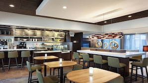Eine moderne Hotelhalle mit Barbereich, Sitzgelegenheiten und einer Rezeption.