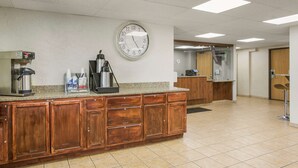 A kitchen area with a coffee machine, a clock, and a wooden counter.