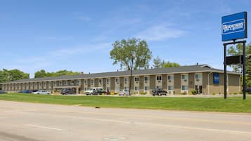 Un motel con una fila di camere, un parcheggio e il cartello Rodeway Inn & Suites.