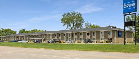 A motel with a row of rooms, a parking lot, and a sign for Rodeway Inn & Suites.