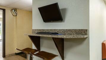 A small office area with a desk, chair, and a mounted flat-screen monitor.