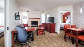A hotel room with a dining area, a television, a fireplace, and a bed.
