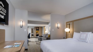 A hotel room with a large bed, a desk with a chair, a sofa, and a TV mounted on the wall. - Fairfield Inn & Suites Fort Worth Downtown/Convention Center (Fort Worth)