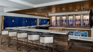 A modern bar area with a long counter, multiple stools, and a refrigerated bar display. - Fairfield Inn & Suites Fort Worth Downtown/Convention Center (Fort Worth)