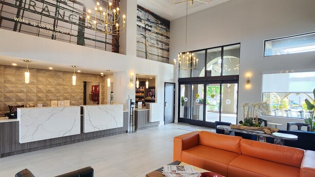 Un hall espacioso con mostrador de recepción, zona de estar y un alto techo con candelabros.