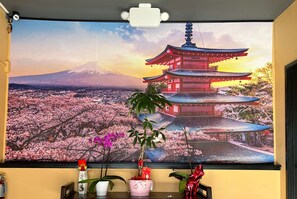 A room with a large window displaying a scenic view of a traditional Japanese pagoda and cherry blossoms.