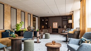 Un espace de détente moderne avec un mur d’accent en briques, des sièges confortables et un mélange de tables rondes et carrées.