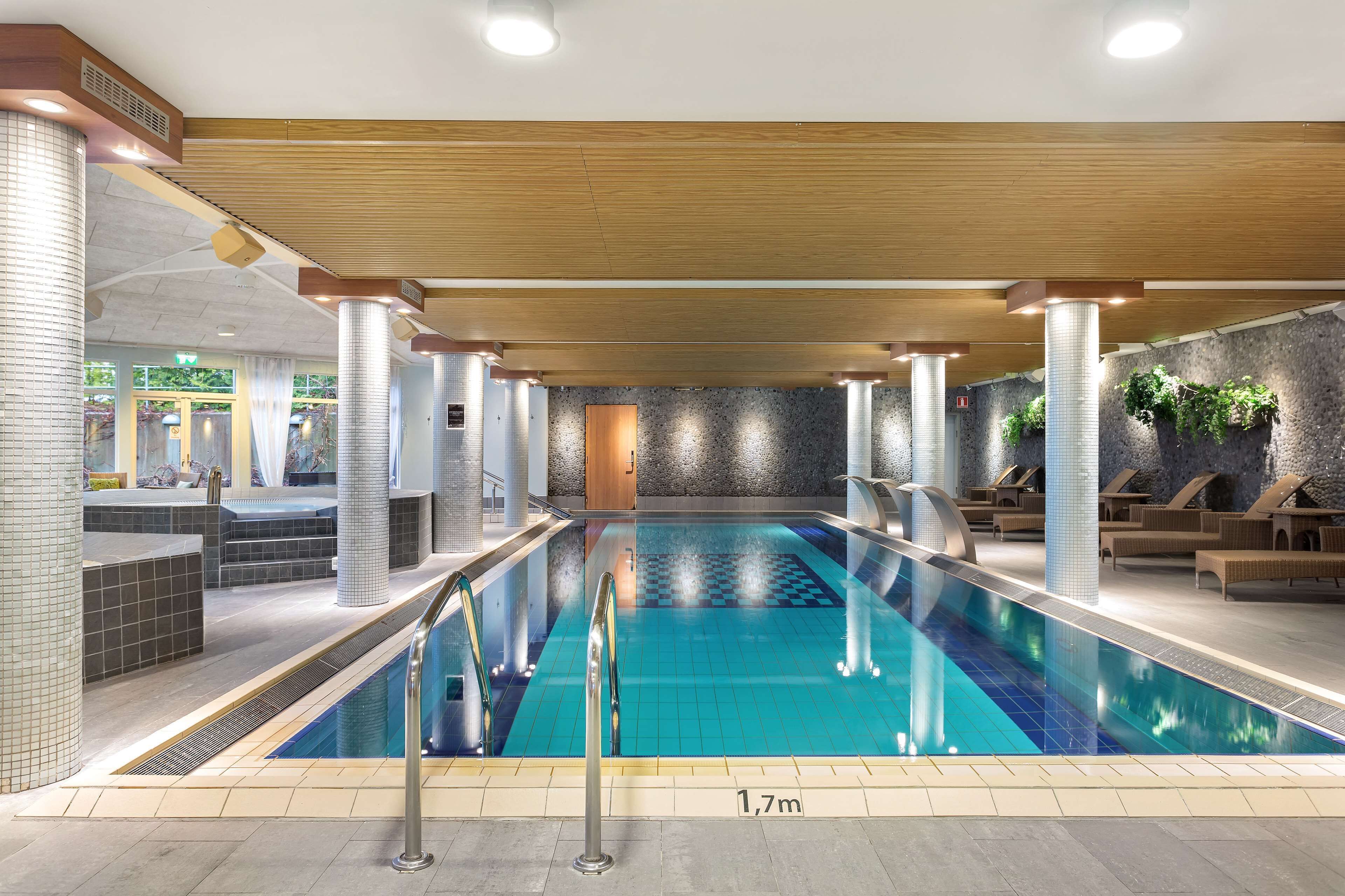 En inomhuspool med ett djup på 1,7 meter, omgiven av solstolar och ett spaområde.