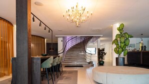 Un hall d’hôtel moderne avec un escalier, un espace salon circulaire et un bar.