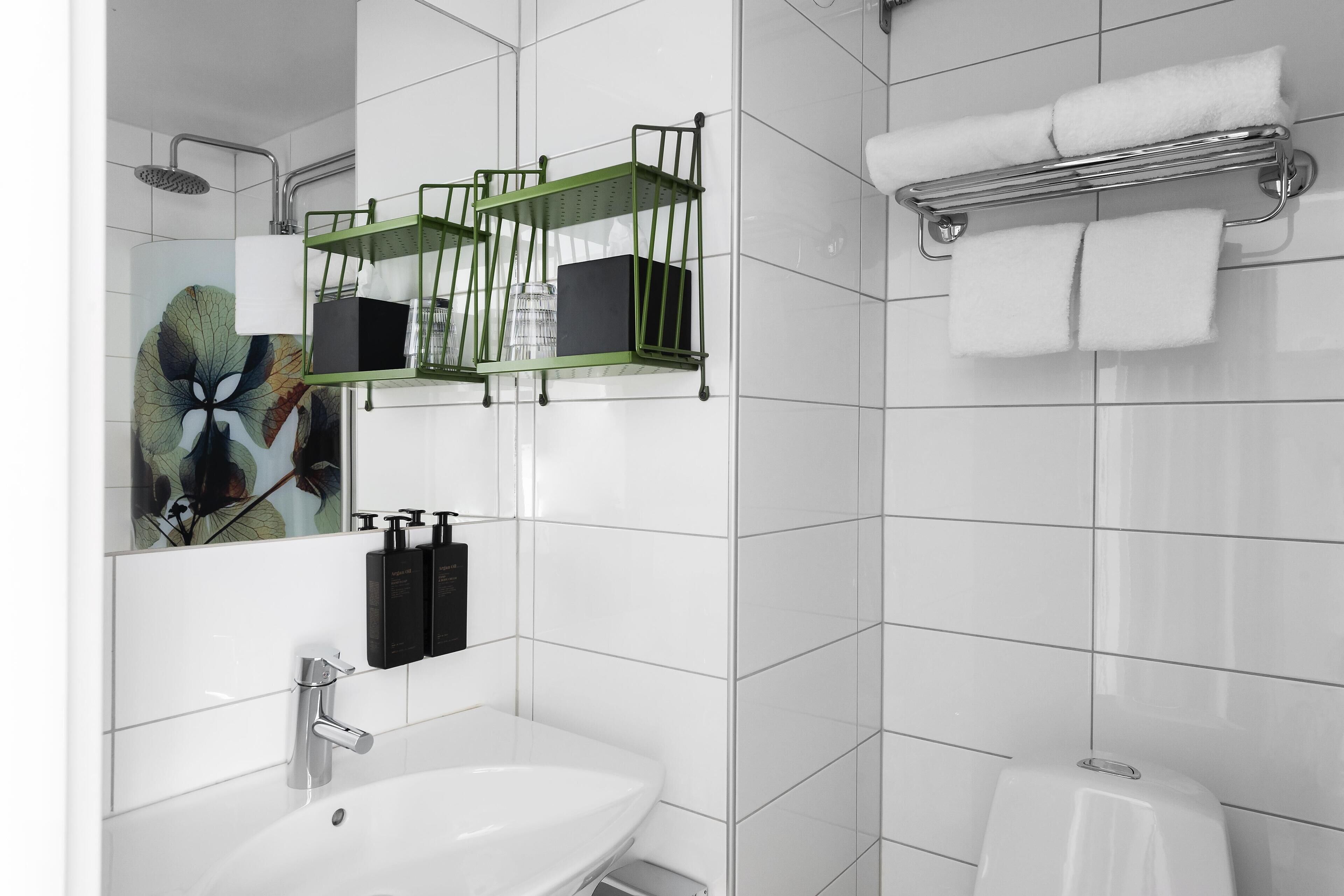 A modern bathroom with a white sink, a mirror, a shower, and a towel rack.