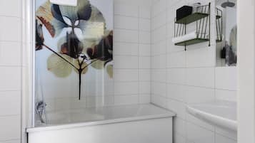 Een badkamer met witte tegels, een glazen douchecabine, een witte wastafel en een handdoekrek.