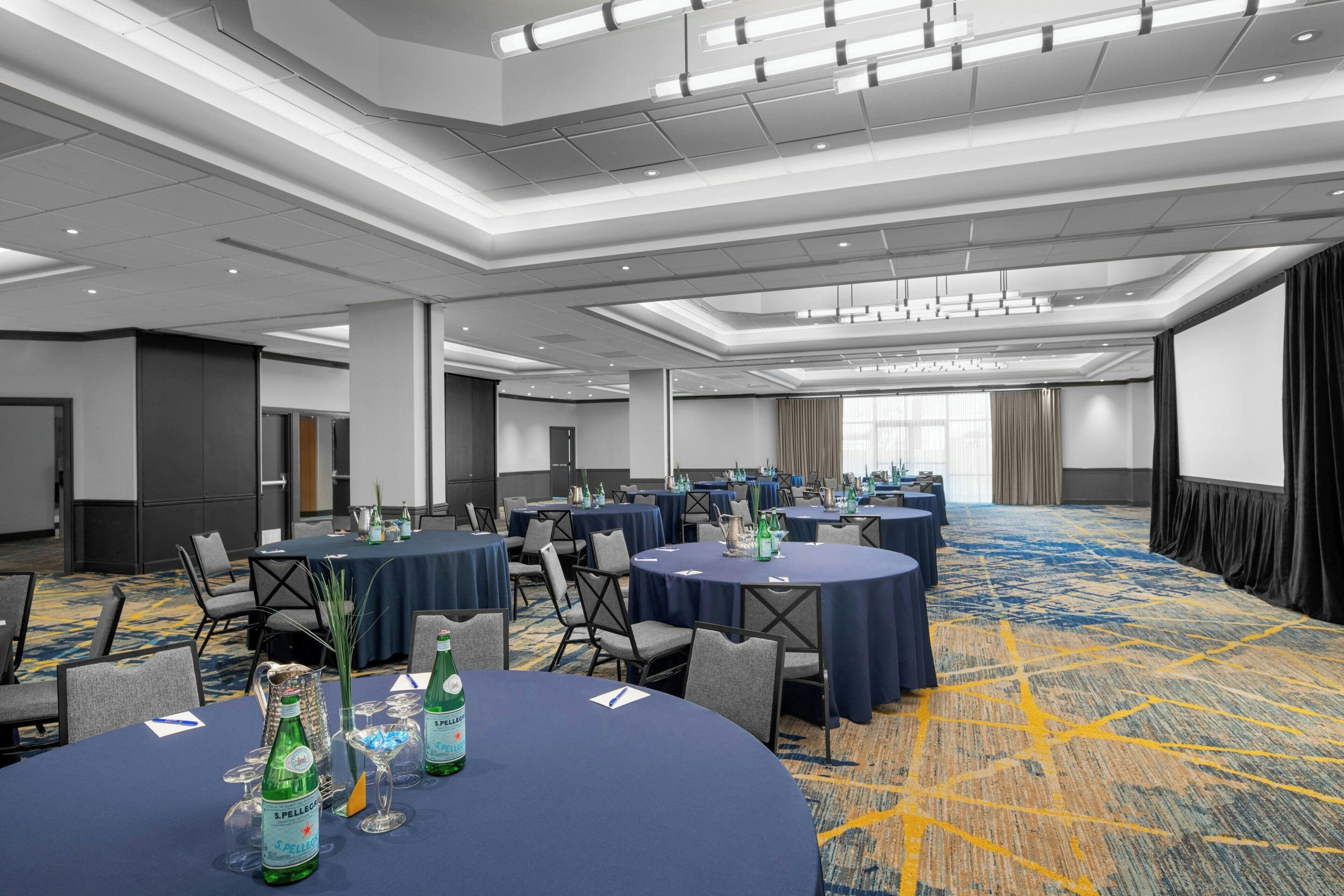 A conference room with round tables, chairs, and a carpeted floor.