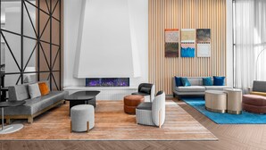 A modern living room with a sofa, ottomans, and a fireplace. -  Delta Hotels by Marriott Santa Clara (Santa Clara)