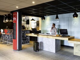Uma receção com design moderno, uma área de bar com tabouretos e um relógio na parede.