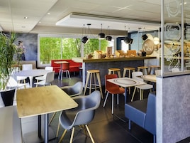 Um café moderno com mesas, cadeiras e balcão.
