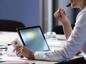 A person holding a card and a pen, sitting at a table with a laptop. - ibis Roanne (Le Coteau)