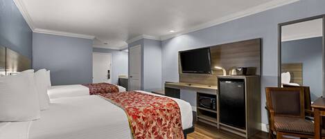 A hotel room with two beds, a TV, a microwave, and a dining area.