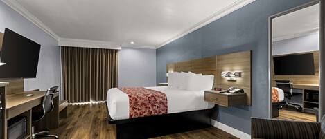 A hotel room with a bed, desk, chair, TV, and a mirror.