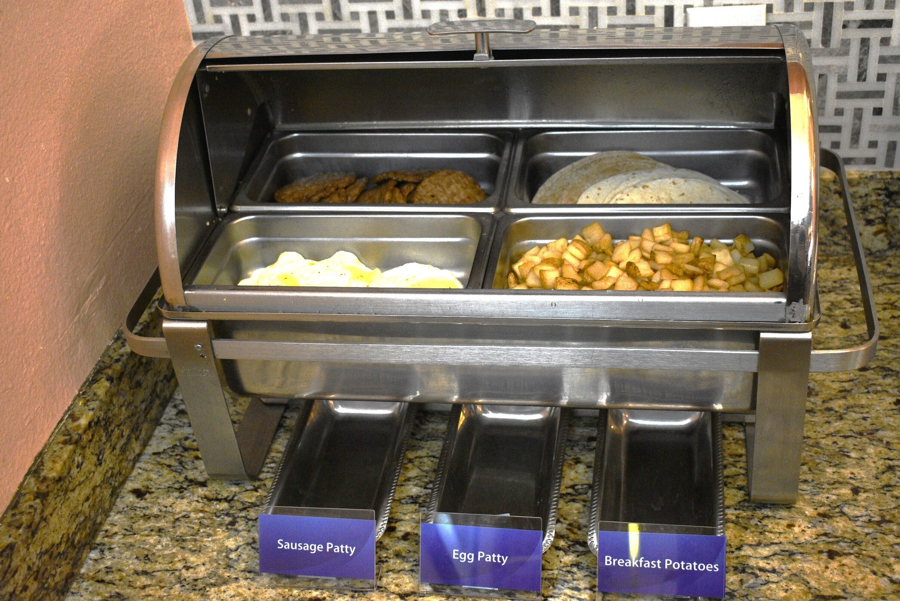 A buffet with labeled sections for sausage patty, egg patty, and breakfast potatoes.