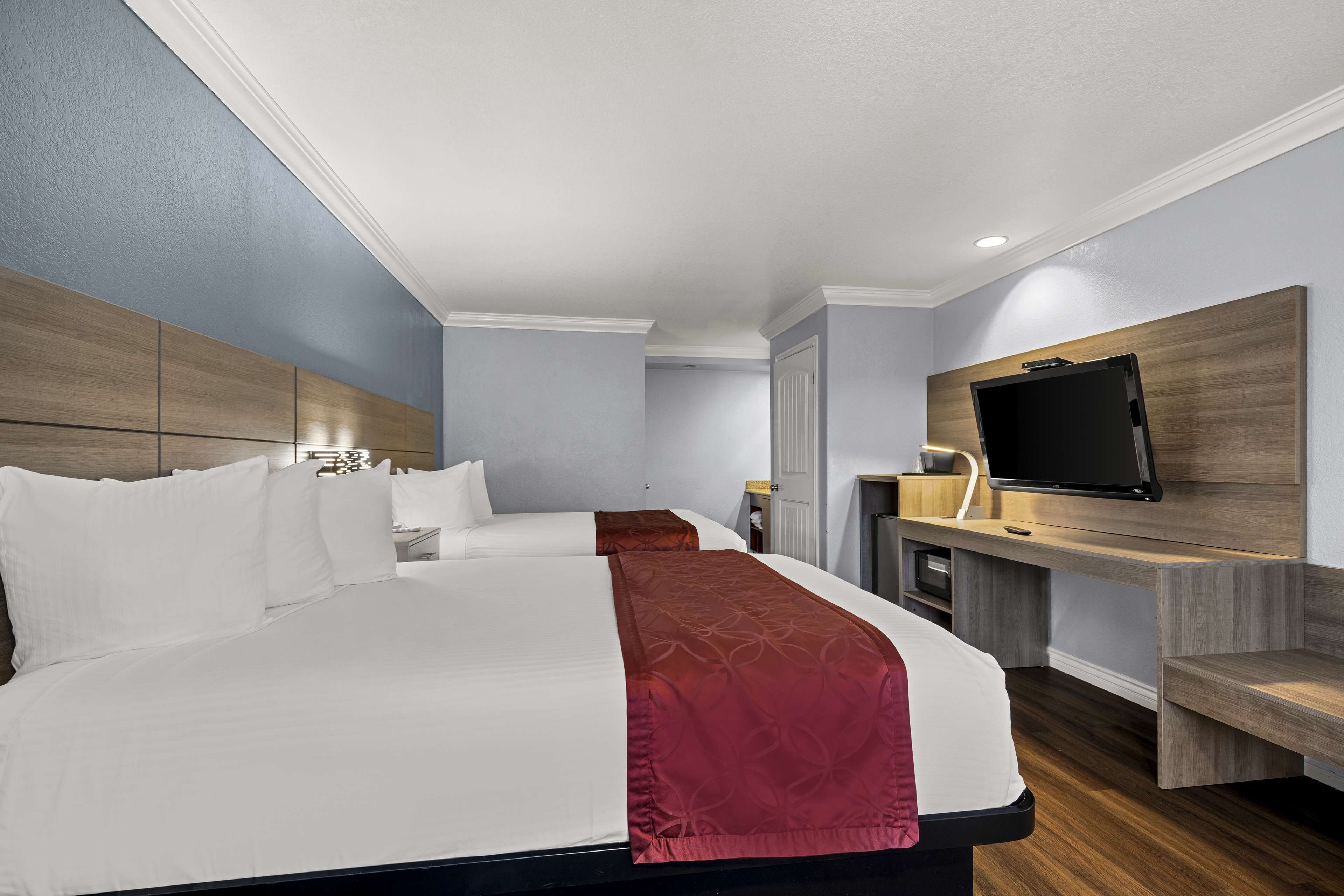 A hotel room with a large bed, a desk with a flat-screen TV, and a wardrobe.