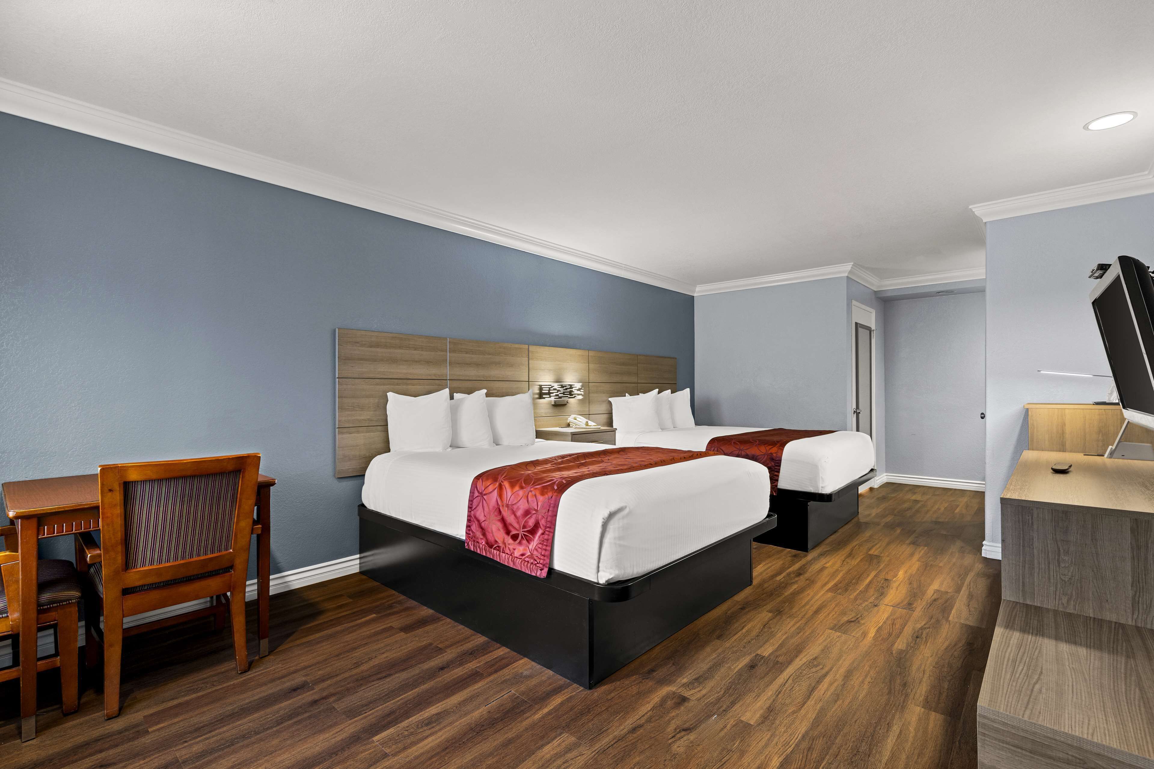 A hotel room with two beds, a desk, and a chair.