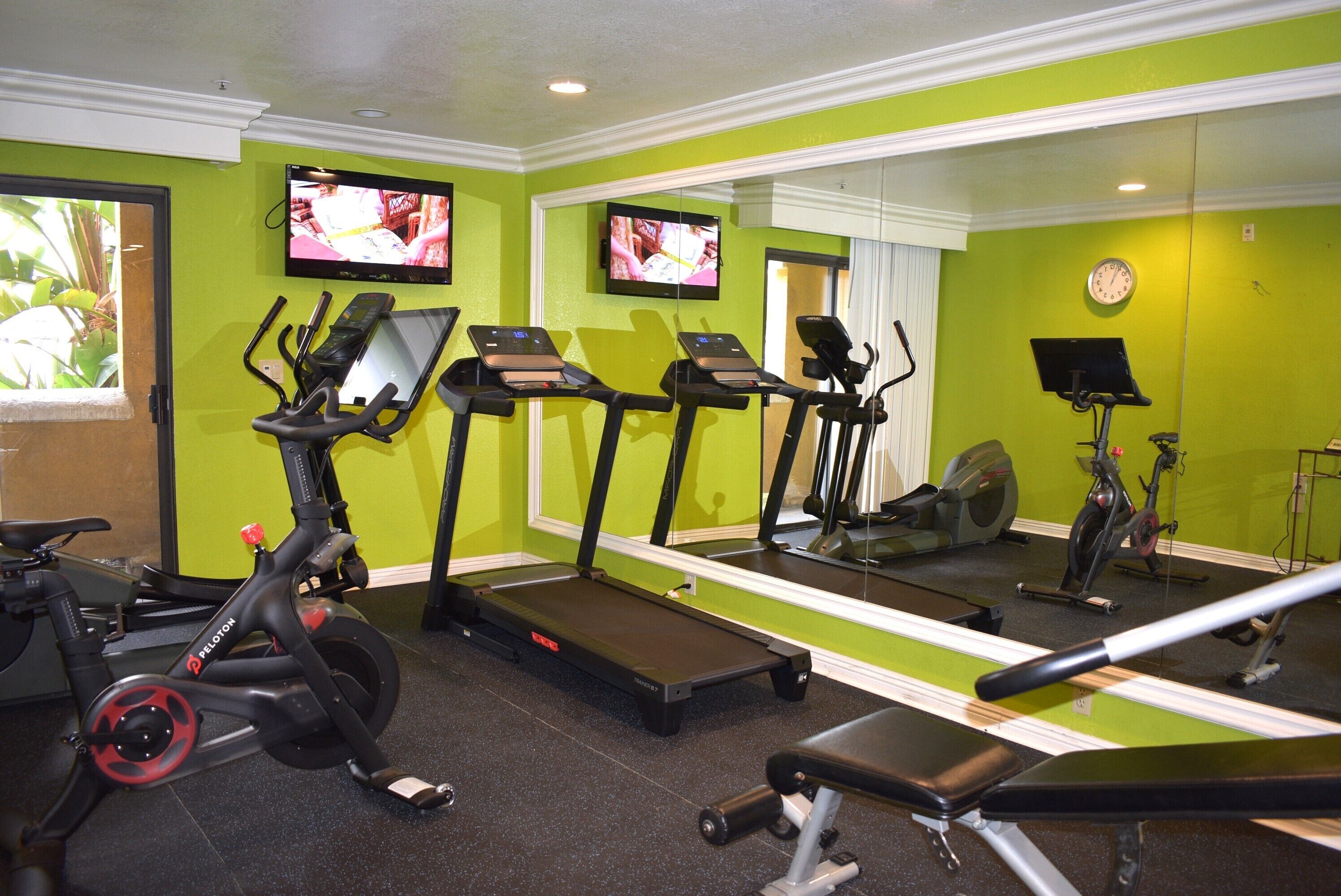 A gym with treadmills, ellipticals, and a bench.